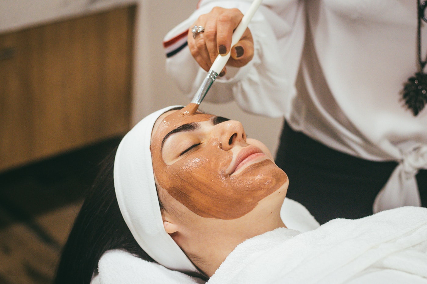A woman smoothing moisturiser onto her cheek — the quiet daily ritual behind every treatment course